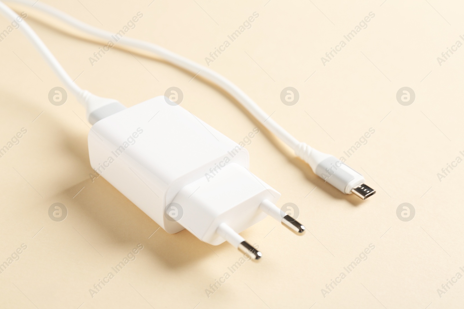 Photo of USB power adapter with charge cable on beige background, closeup