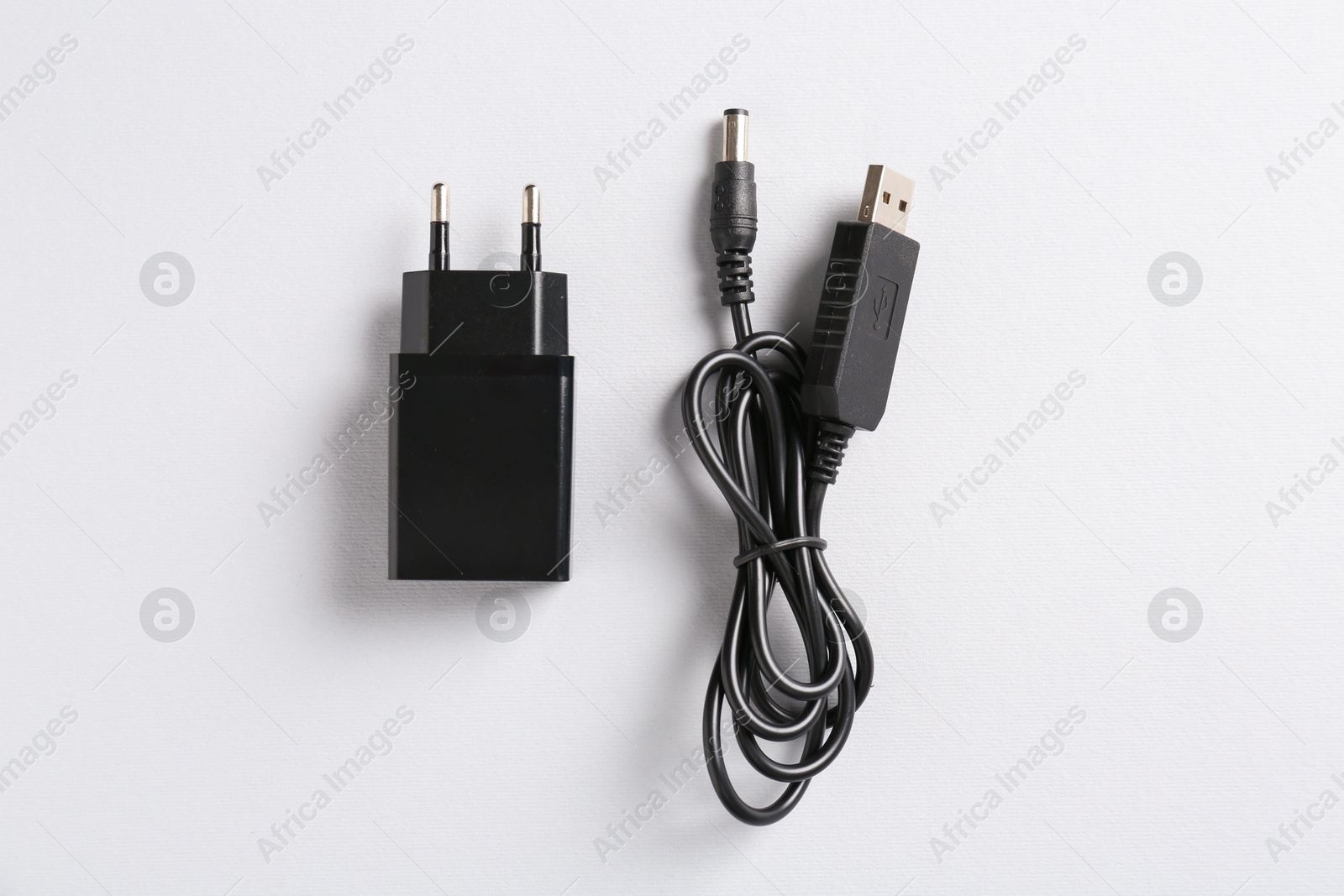 Photo of USB power adapter and charge cable on white background, flat lay