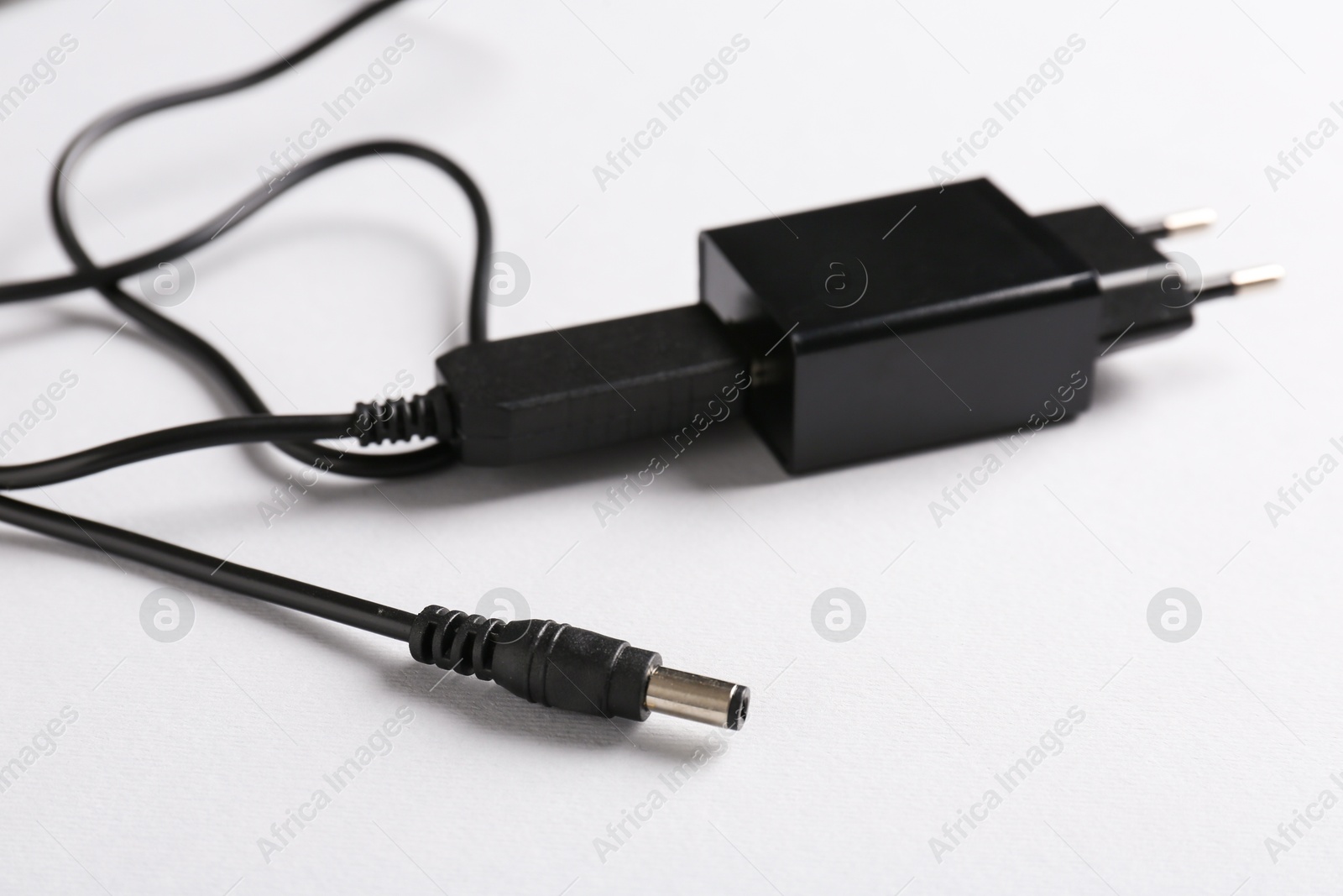 Photo of USB power adapter with charge cable on white background, closeup. Space for text