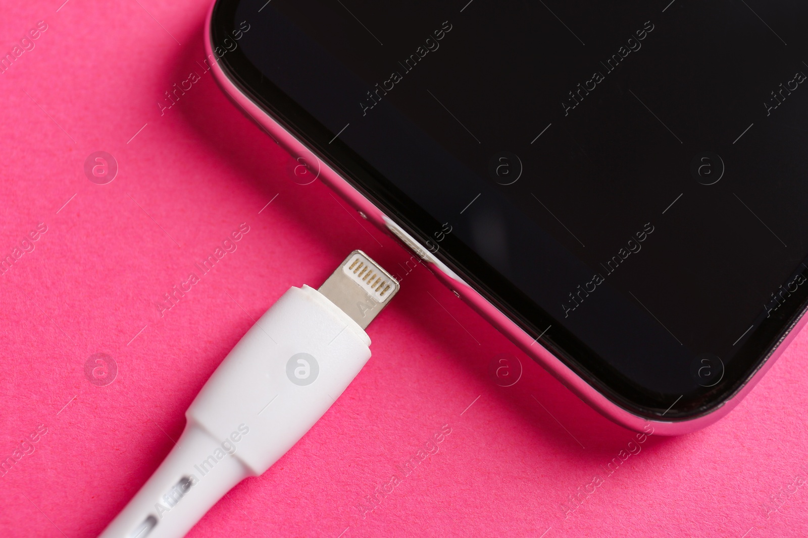 Photo of USB charge cable and smartphone on pink background, above view