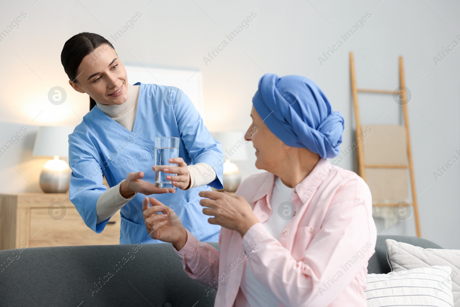 Photo of Nurse giving water to woman with cancer at home