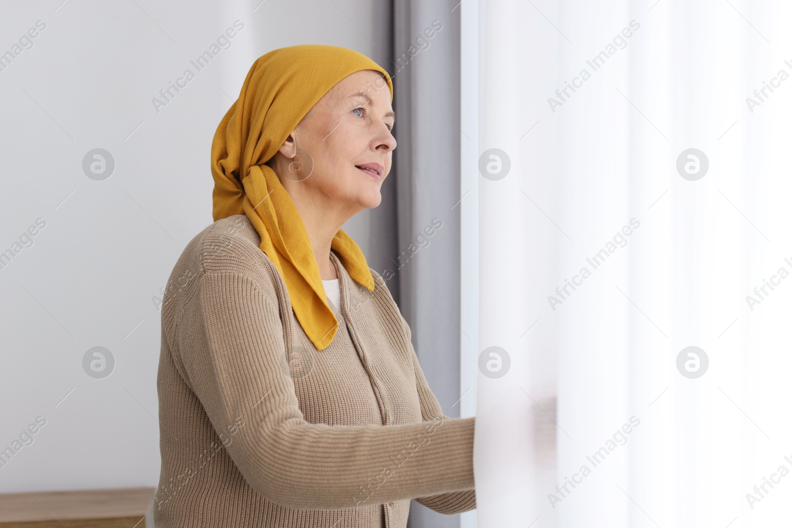 Photo of Senior woman with cancer near window at home