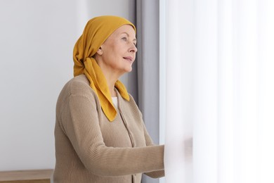 Senior woman with cancer near window at home