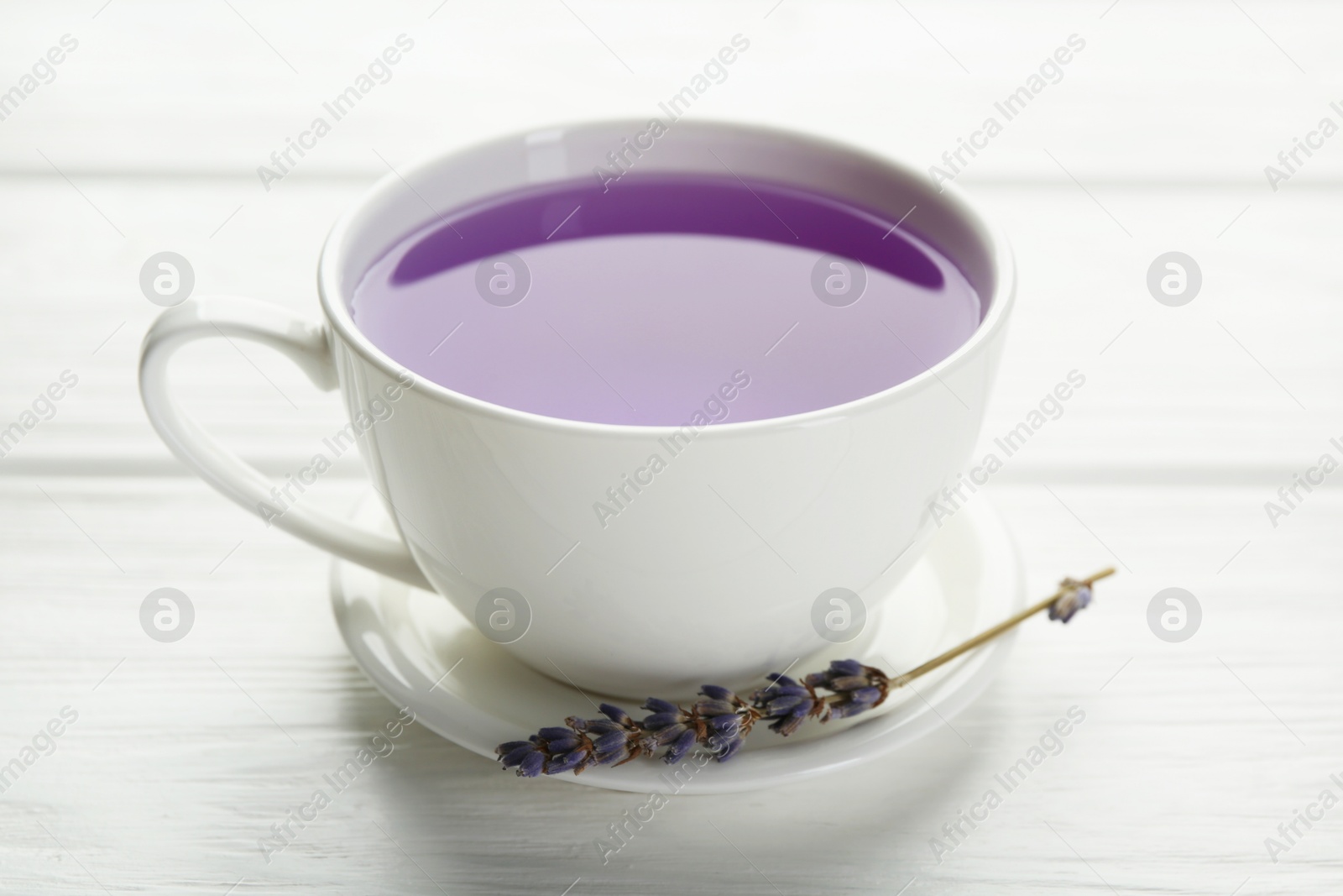 Aromatic lavender tea in cup and dry flowers on white wooden table, closeup Photo of Aromatic lavender tea in cup and dry flowers on white wooden table, closeup