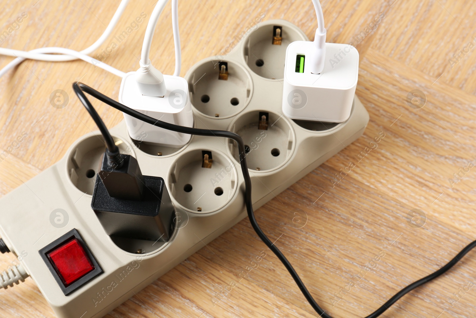 Photo of USB adapters with charge cables in power strip on wooden table, above view