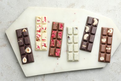 Photo of Delicious chocolate bars with different flavors on light table, top view