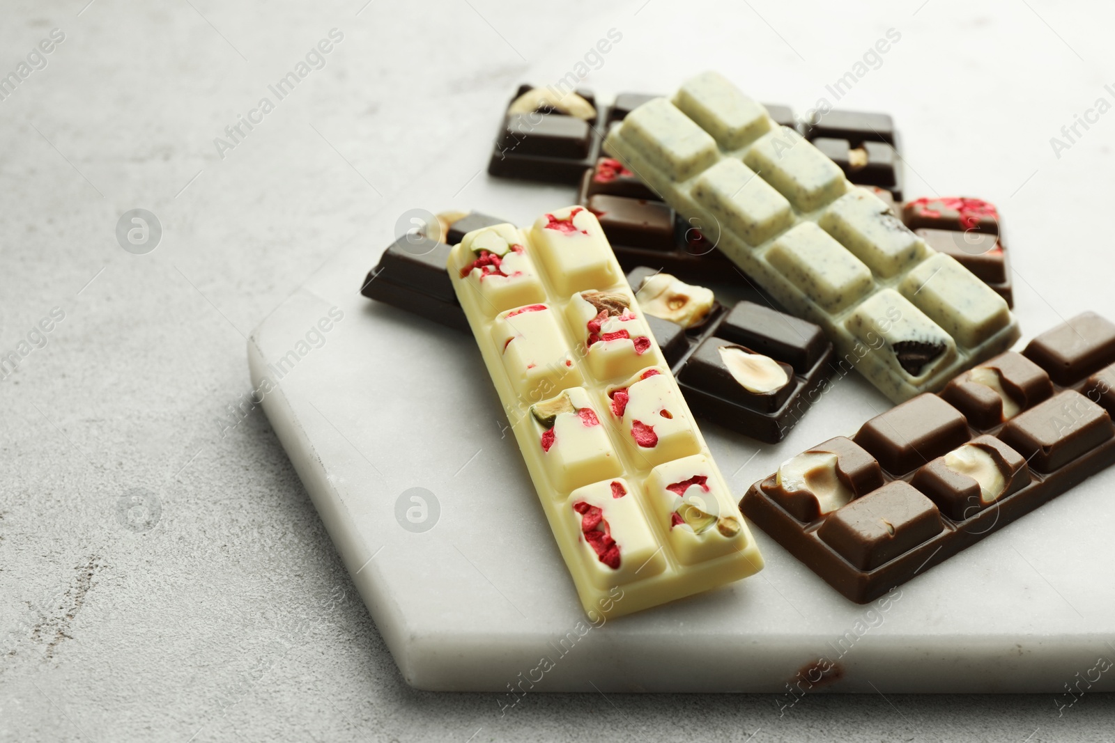 Photo of Delicious chocolate bars with different flavors on light table, closeup