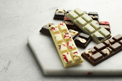 Delicious chocolate bars with different flavors on light table, closeup