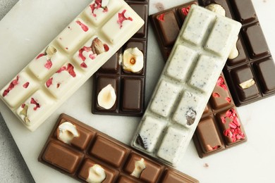 Delicious chocolate bars with different flavors on light table, closeup