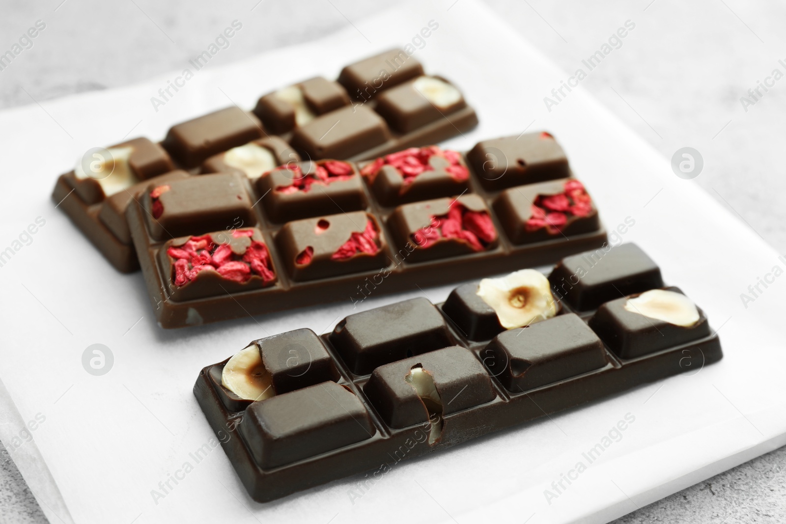 Photo of Delicious chocolate bars with different flavors on light table, closeup