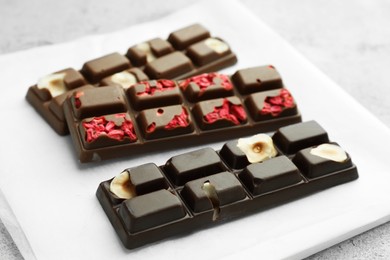 Photo of Delicious chocolate bars with different flavors on light table, closeup