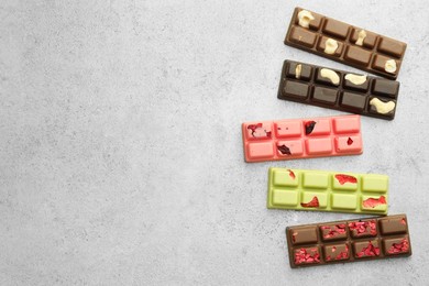 Photo of Delicious chocolate bars with different flavors on light table, flat lay. Space for text