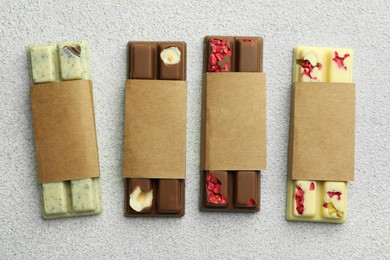 Delicious chocolate bars with different flavors on light table, flat lay