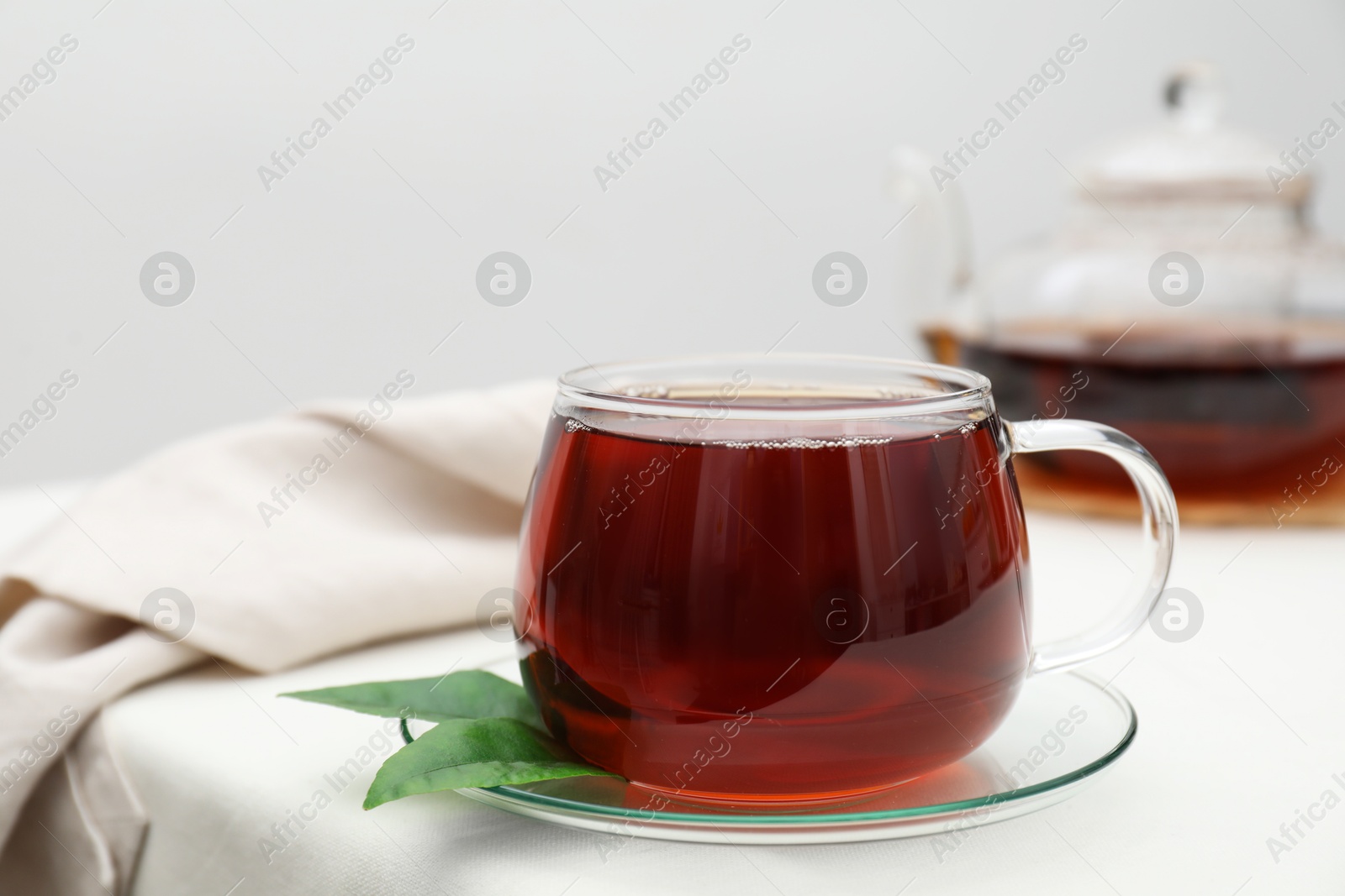 Photo of Refreshing black tea in cup on light table, closeup