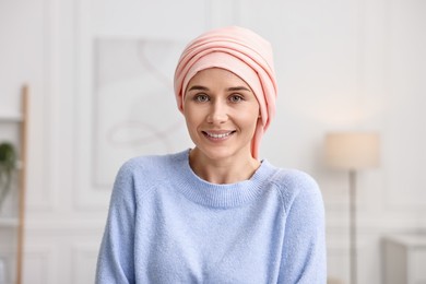 Portrait of smiling woman with cancer in headscarf indoors