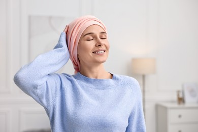 Photo of Portrait of smiling woman with cancer in headscarf indoors