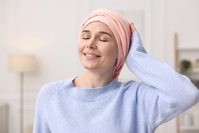 Photo of Portrait of smiling woman with cancer in headscarf indoors