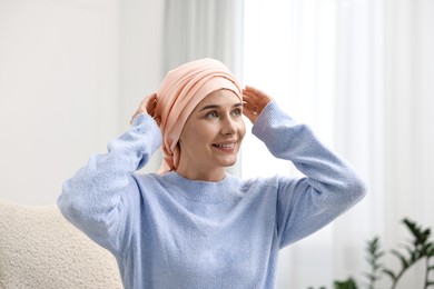 Portrait of smiling woman with cancer in headscarf indoors