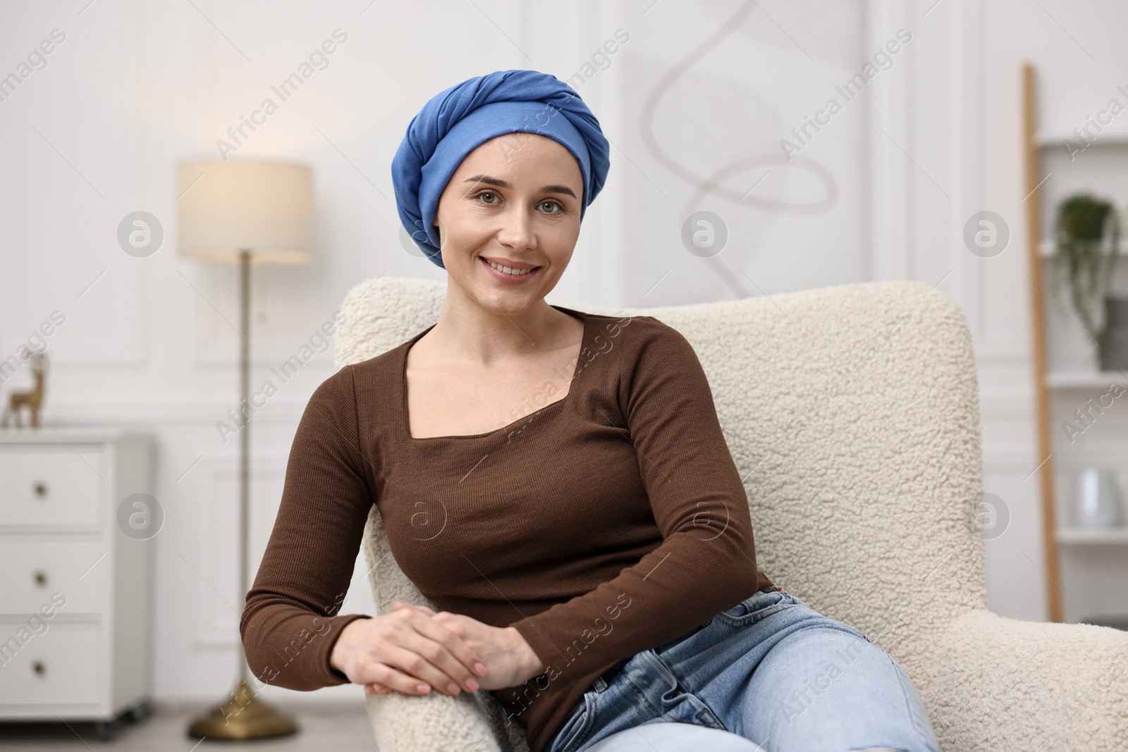 Photo of Portrait of smiling woman with cancer in headscarf on armchair indoors