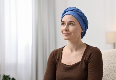 Photo of Young woman with cancer in headscarf on armchair indoors. Space for text