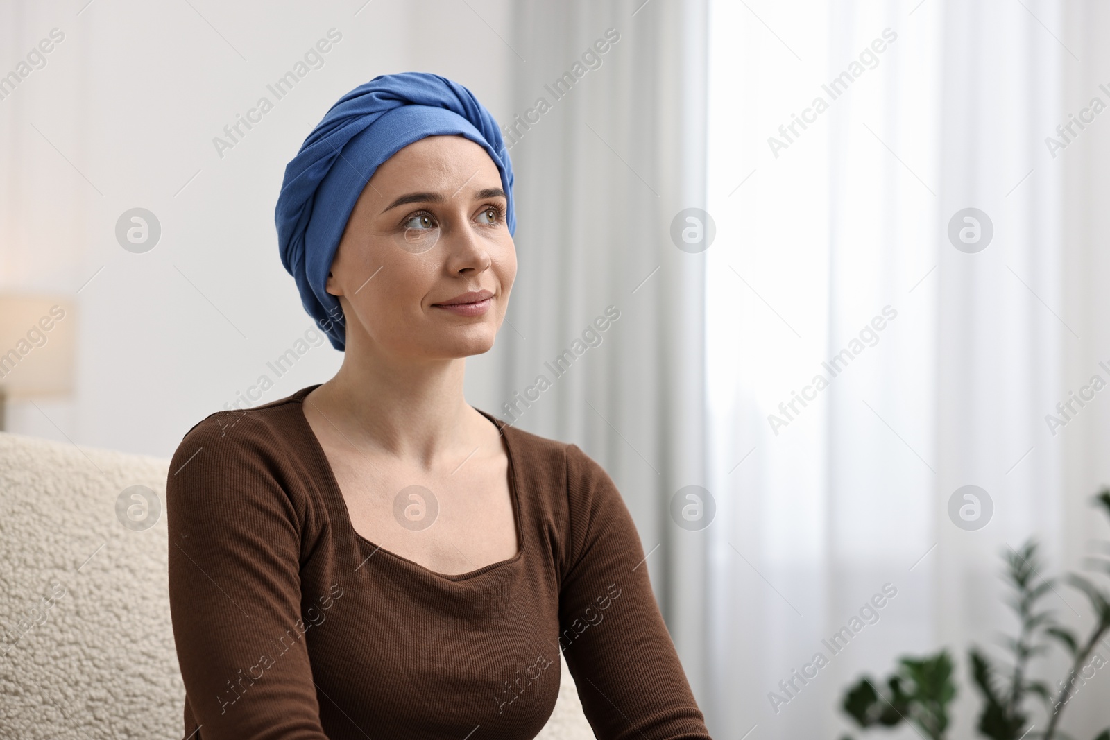 Photo of Young woman with cancer in headscarf on armchair indoors. Space for text