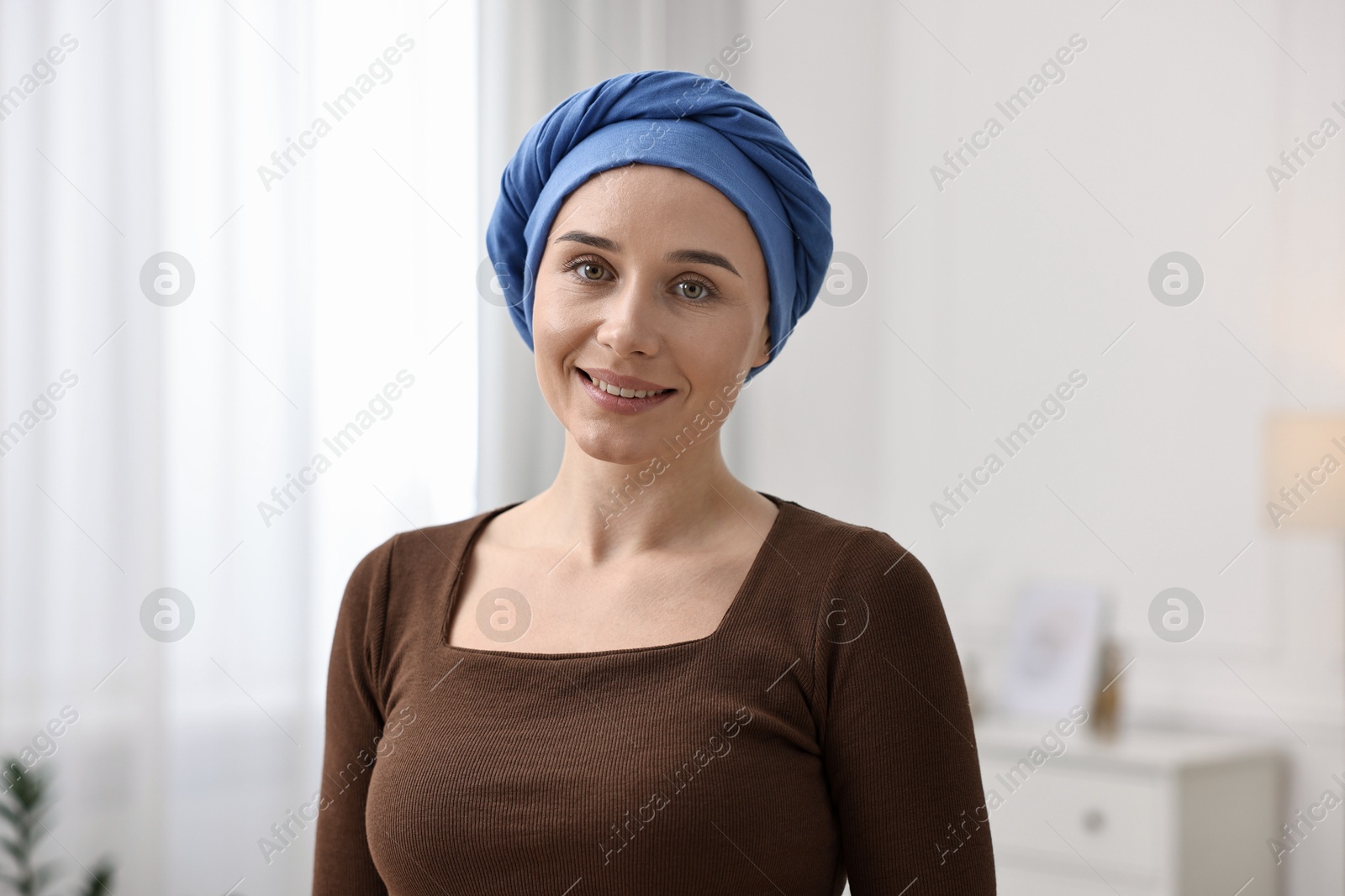 Photo of Portrait of smiling woman with cancer in headscarf indoors