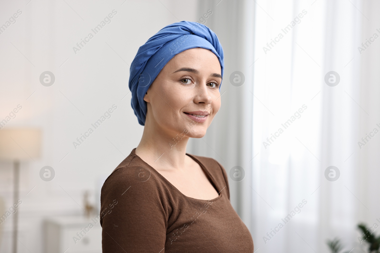 Photo of Portrait of smiling woman with cancer in headscarf indoors