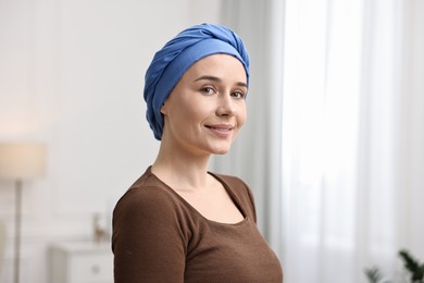 Portrait of smiling woman with cancer in headscarf indoors