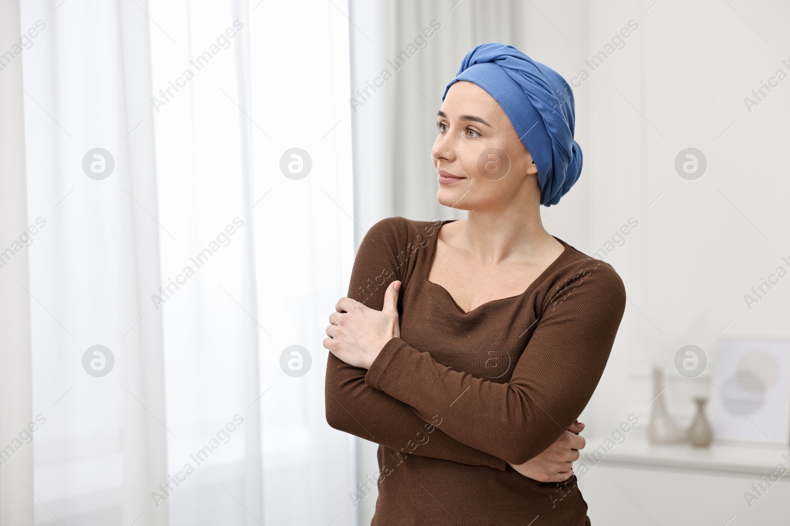 Photo of Portrait of young woman with cancer in headscarf indoors. Space for text