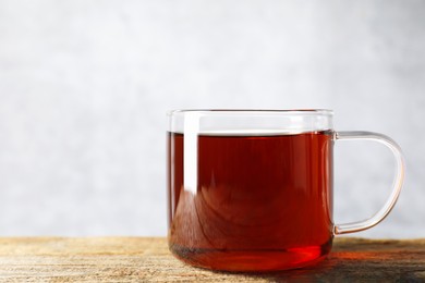 Photo of Aromatic black tea in cup on wooden table, closeup. Space for text