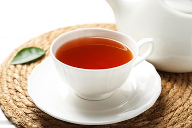 Photo of Aromatic black tea in cup and teapot on white table, closeup