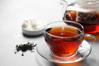 Aromatic black tea, dry leaves and sugar on light table, closeup