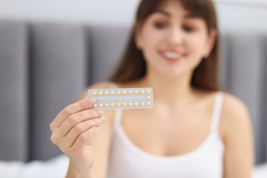 Photo of Woman with blister of contraceptive pills indoors, selective focus