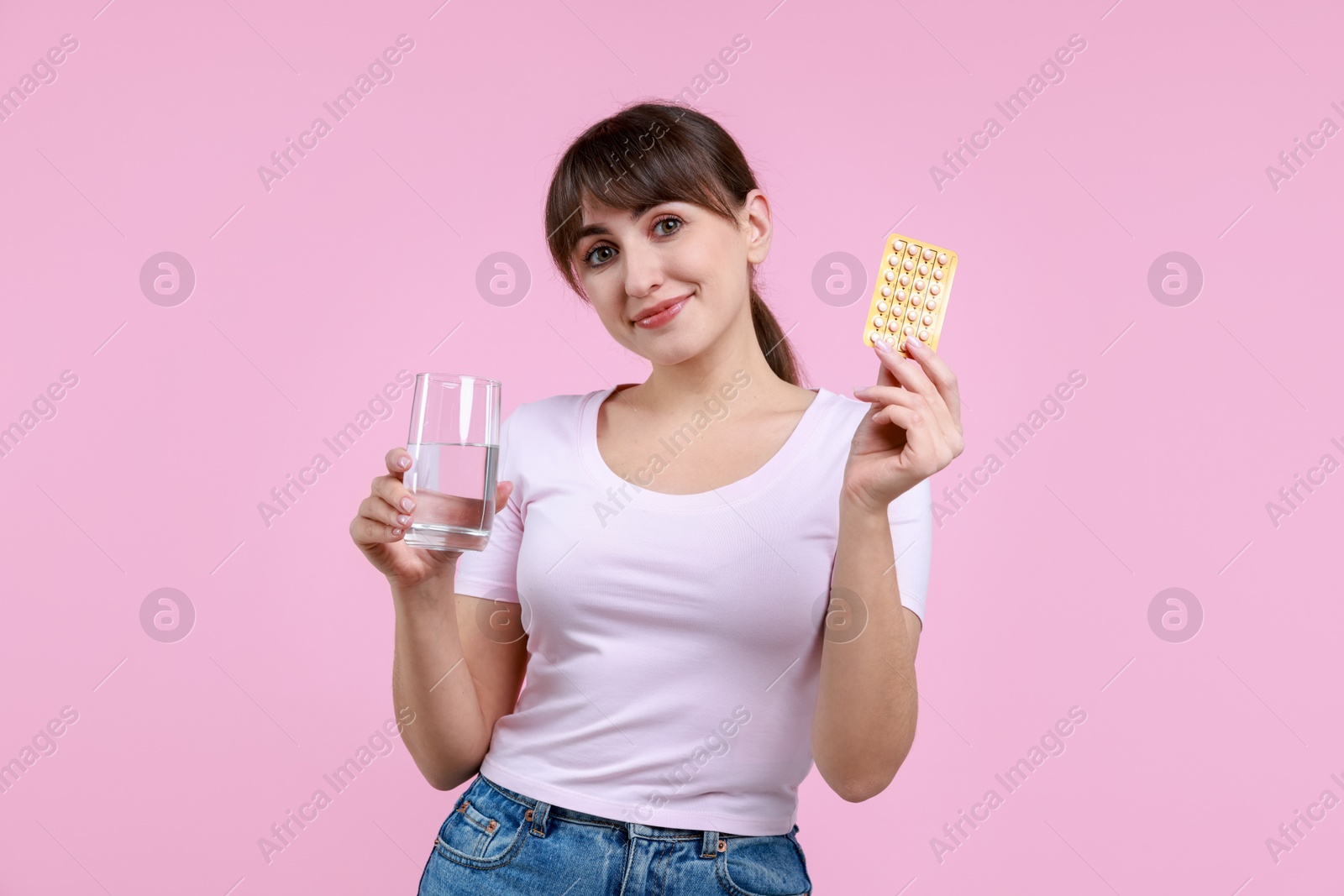 Photo of Young woman with contraceptive pills and glass of water on pink background