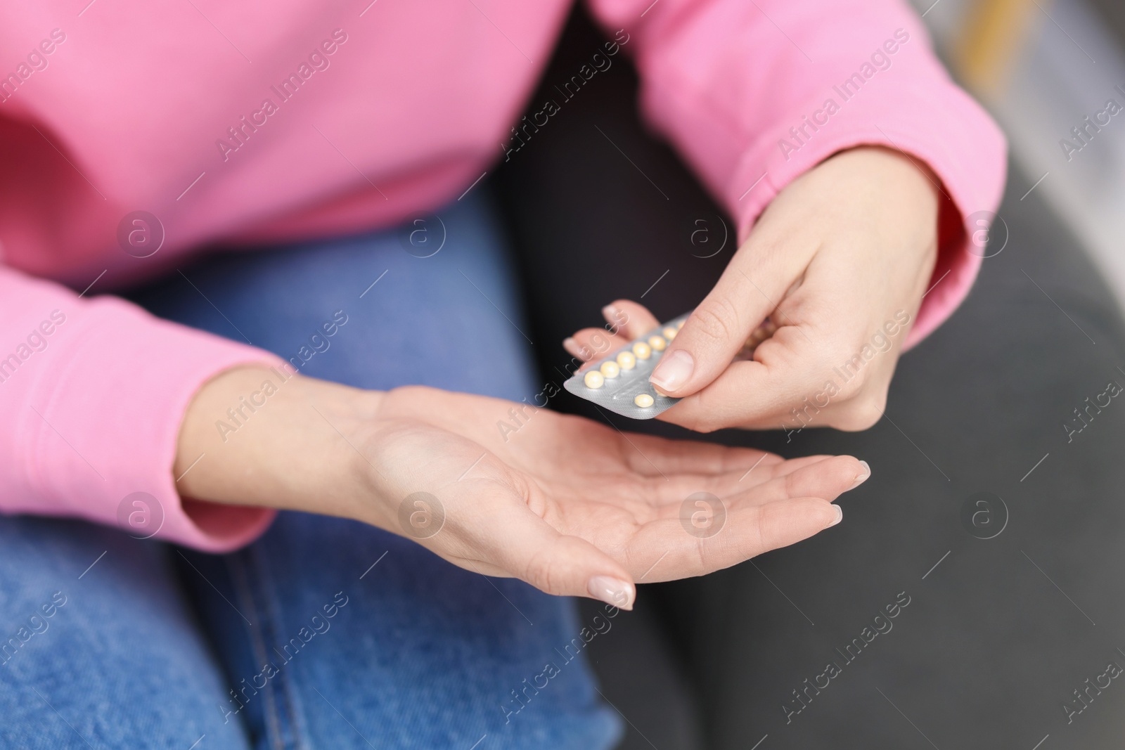 Photo of Woman taking contraceptive pill out from blister indoors, closeup