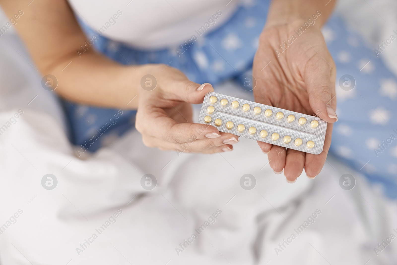 Photo of Woman with blister of contraceptive pills on bed, top view