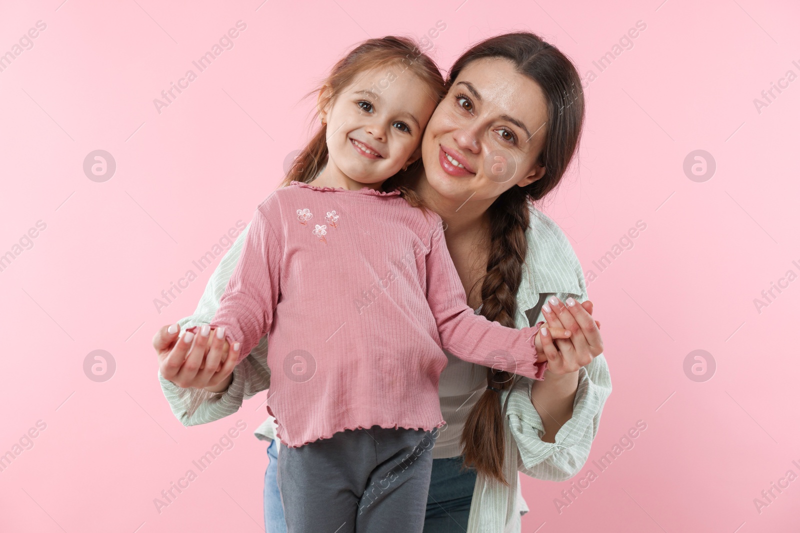 Photo of Family portrait of beautiful mother with little daughter on pink background