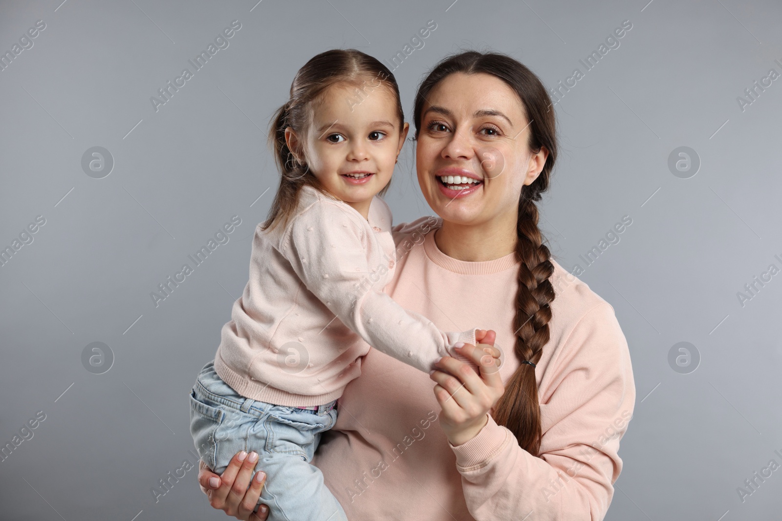 Photo of Family portrait of happy mother with little daughter on grey background