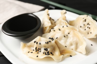 Photo of Delicious gyoza dumplings with sesame seeds served on table, closeup