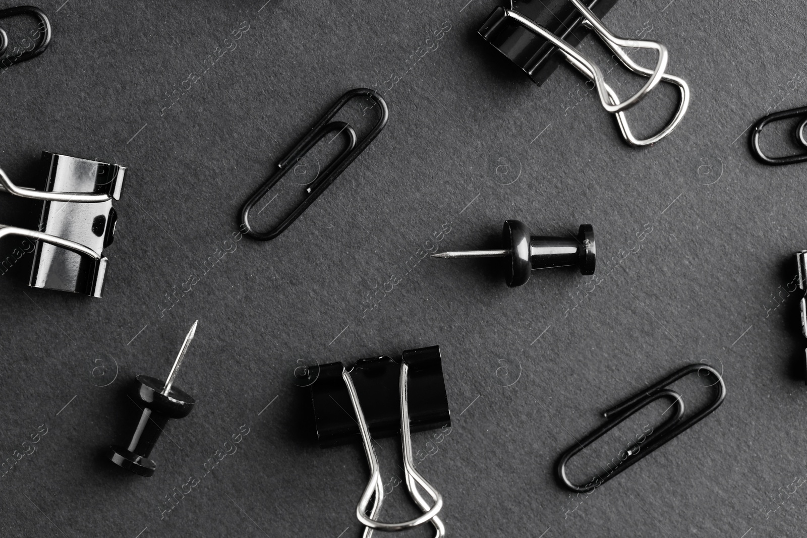 Photo of Paper clips and pins on black background, flat lay