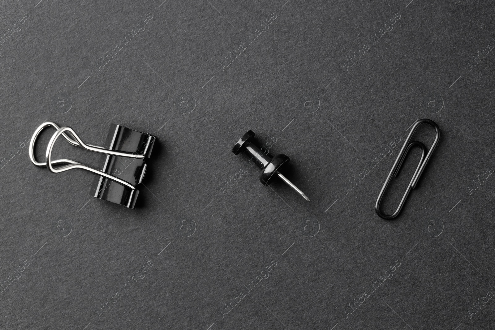 Photo of Paper clips and pin on black background, flat lay