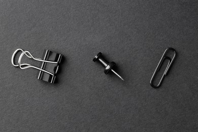 Photo of Paper clips and pin on black background, flat lay