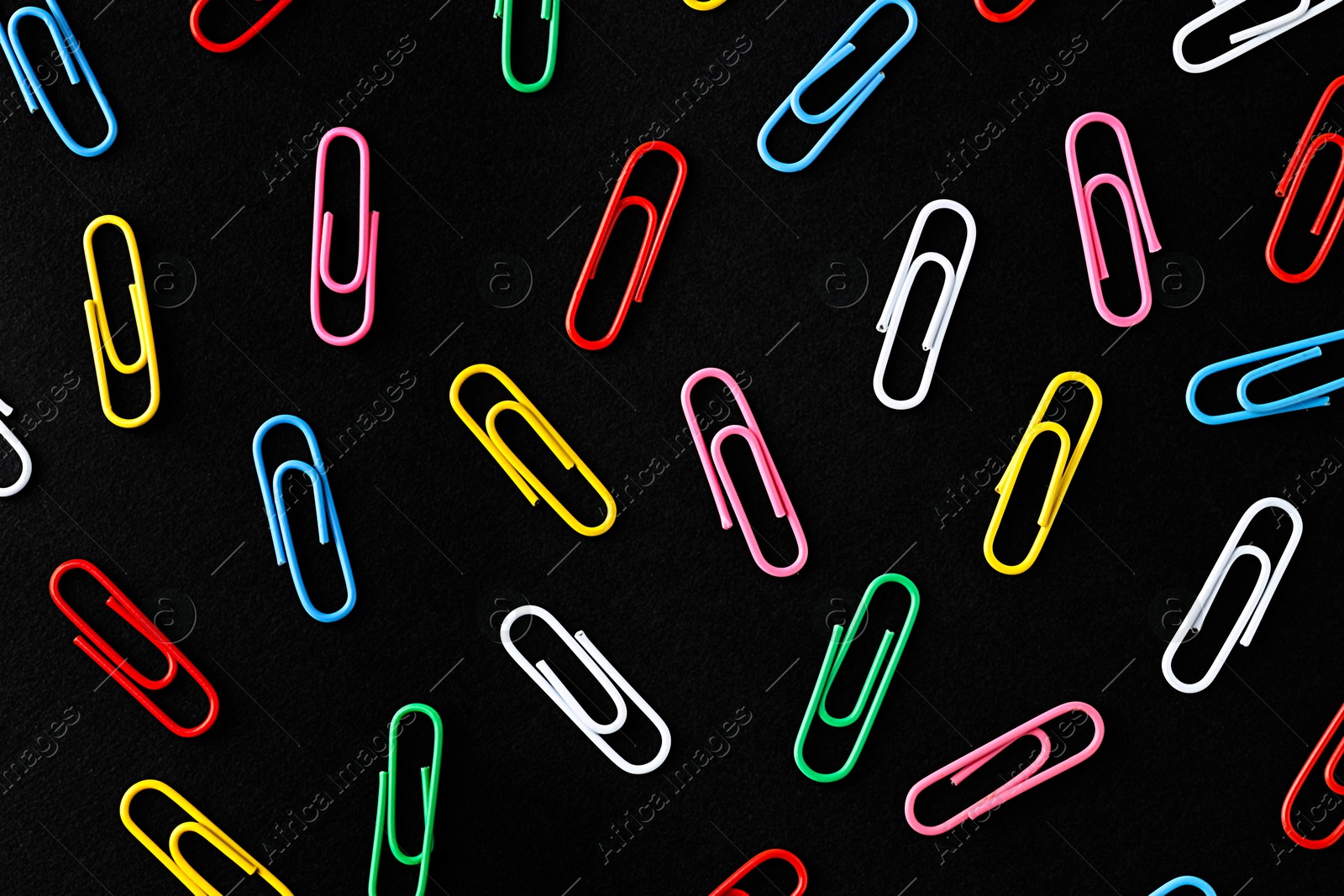 Photo of Colorful paper clips on black background, flat lay