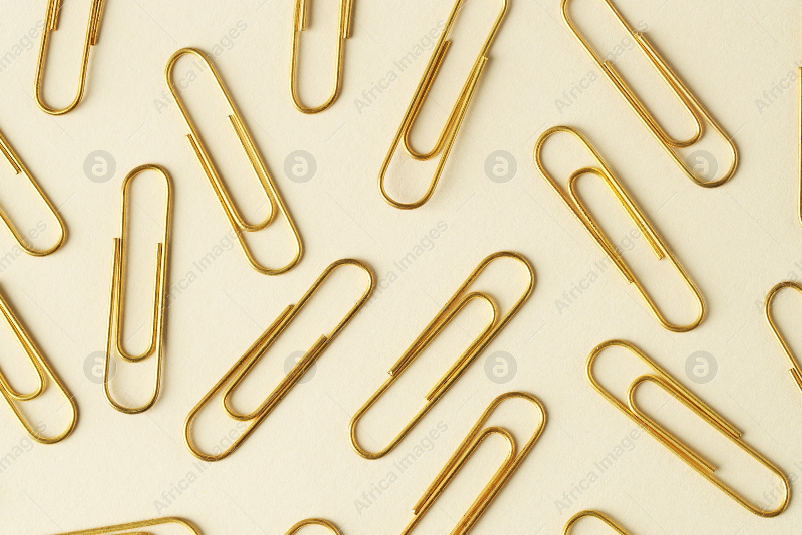 Photo of Golden paper clips on beige background, flat lay