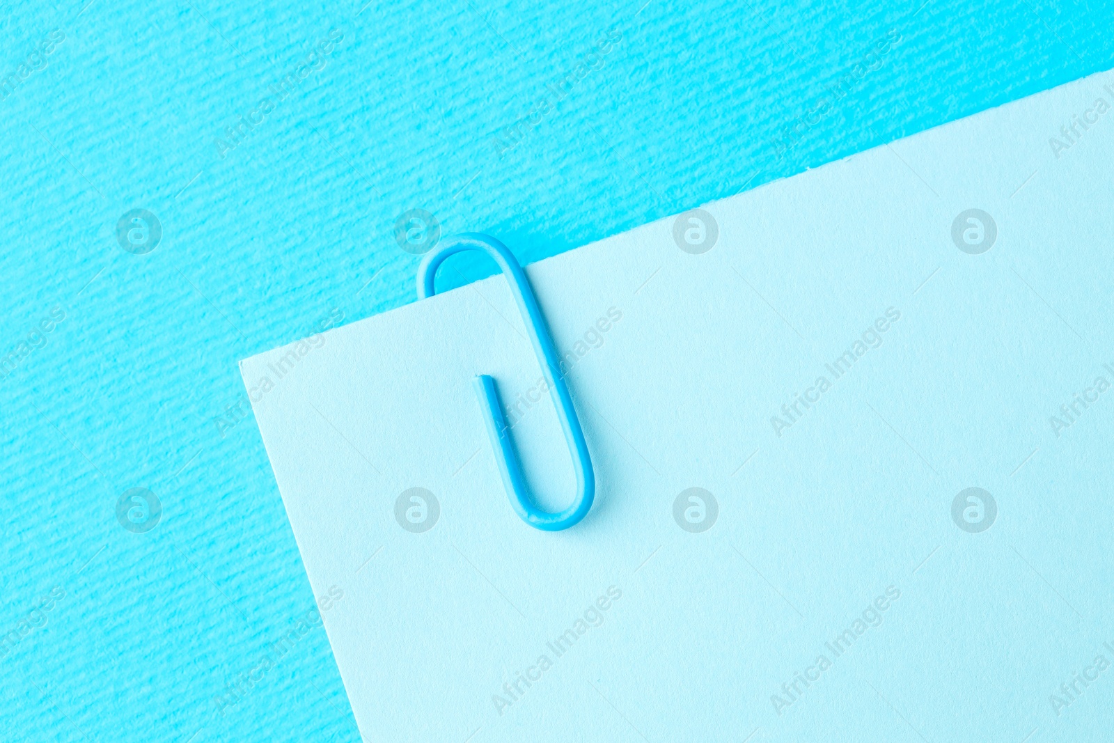 Photo of Paper note with clip on light blue background, top view