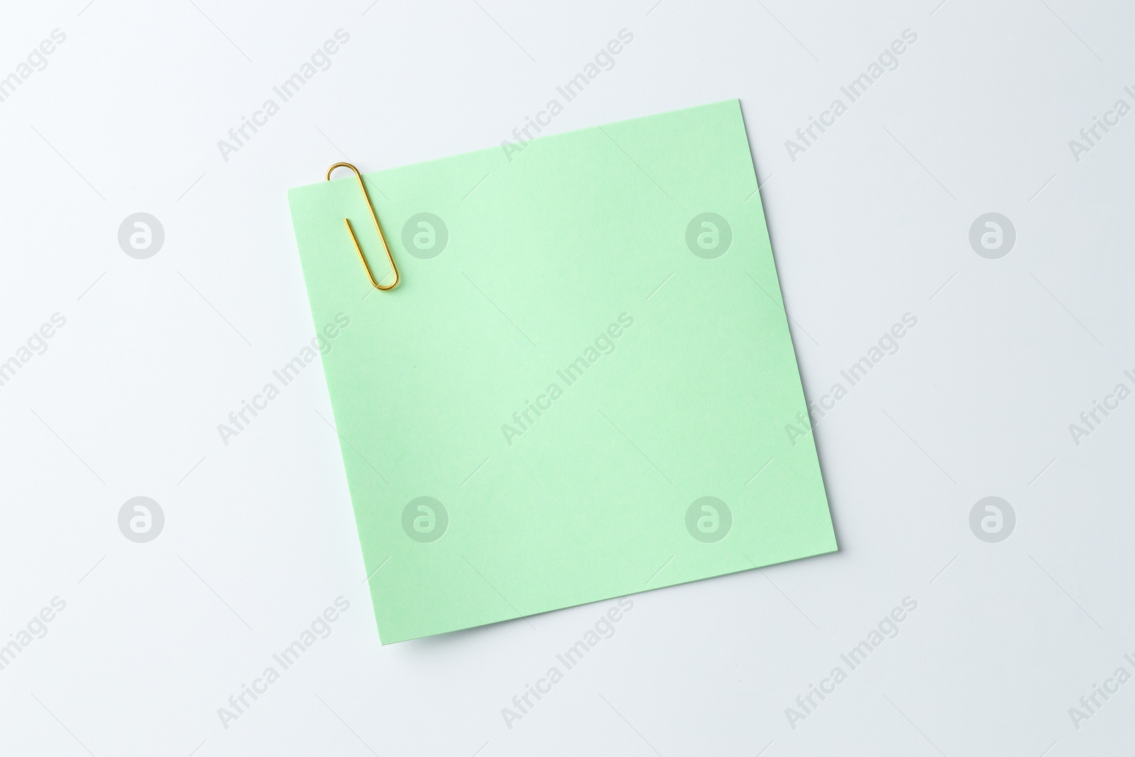 Photo of Paper note with clip on light background, top view. Space for text