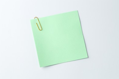 Paper note with clip on light background, top view. Space for text