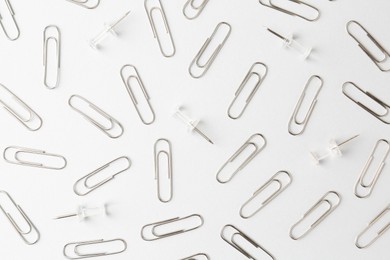 Metal paper clips on light background, flat lay