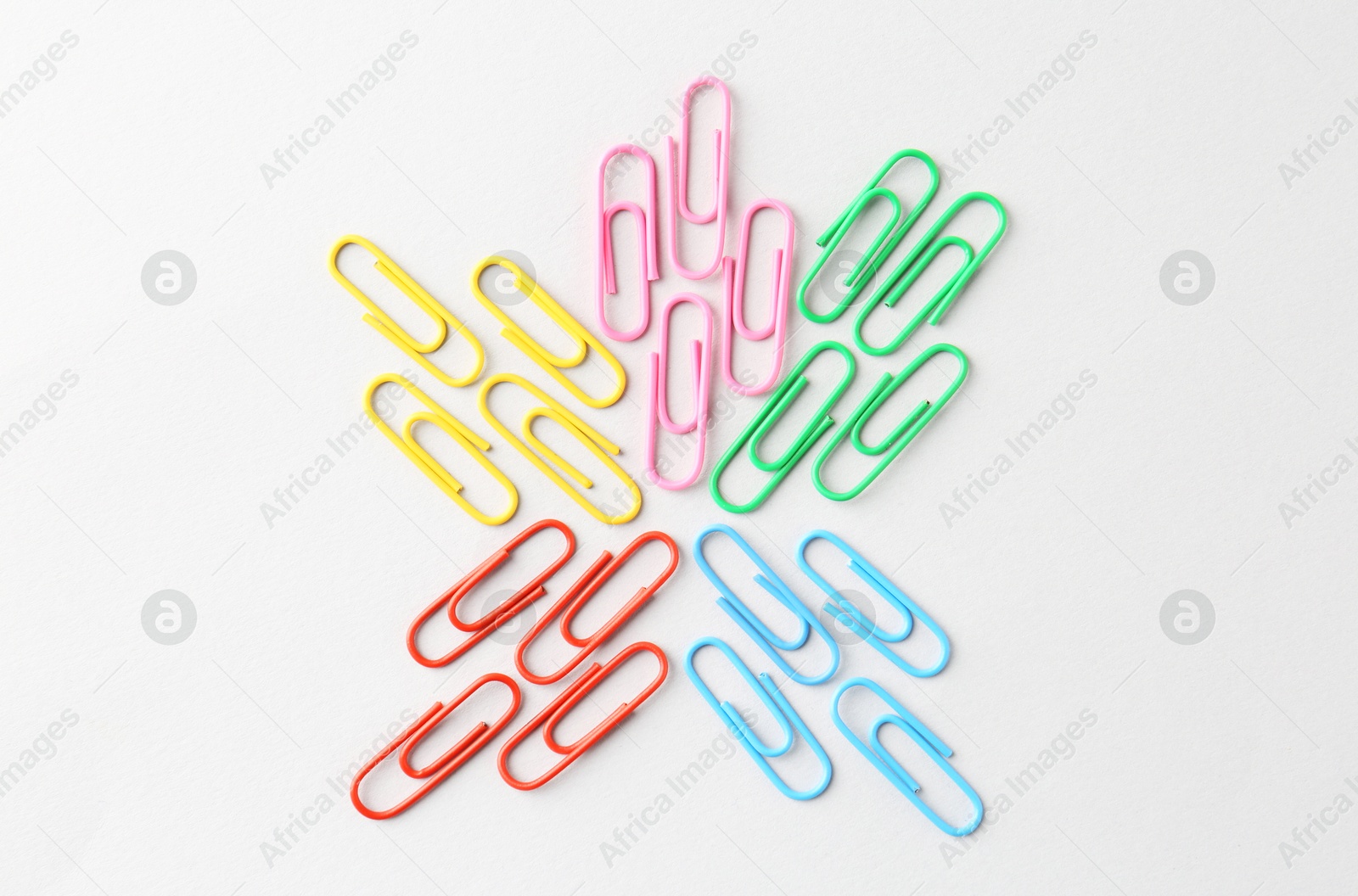 Photo of Colorful paper clips on light background, flat lay