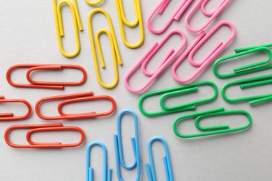 Photo of Colorful paper clips on light background, flat lay